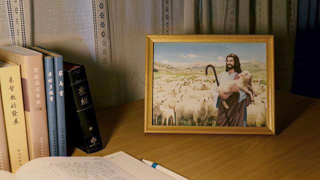 桌子上放着圣经书和主耶稣抱着小羊的画像