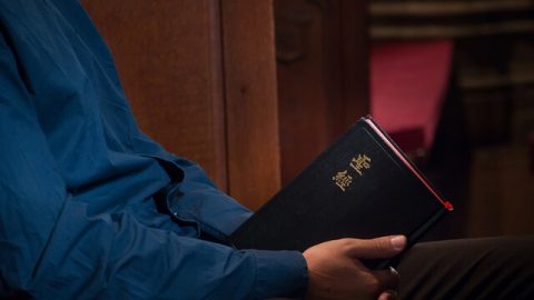 做在教堂手拿圣经沉思