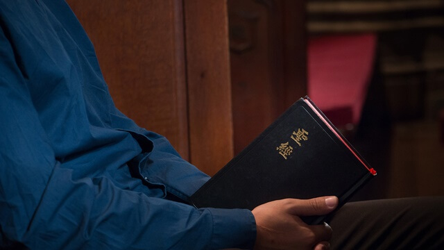 做在教堂手拿圣经沉思